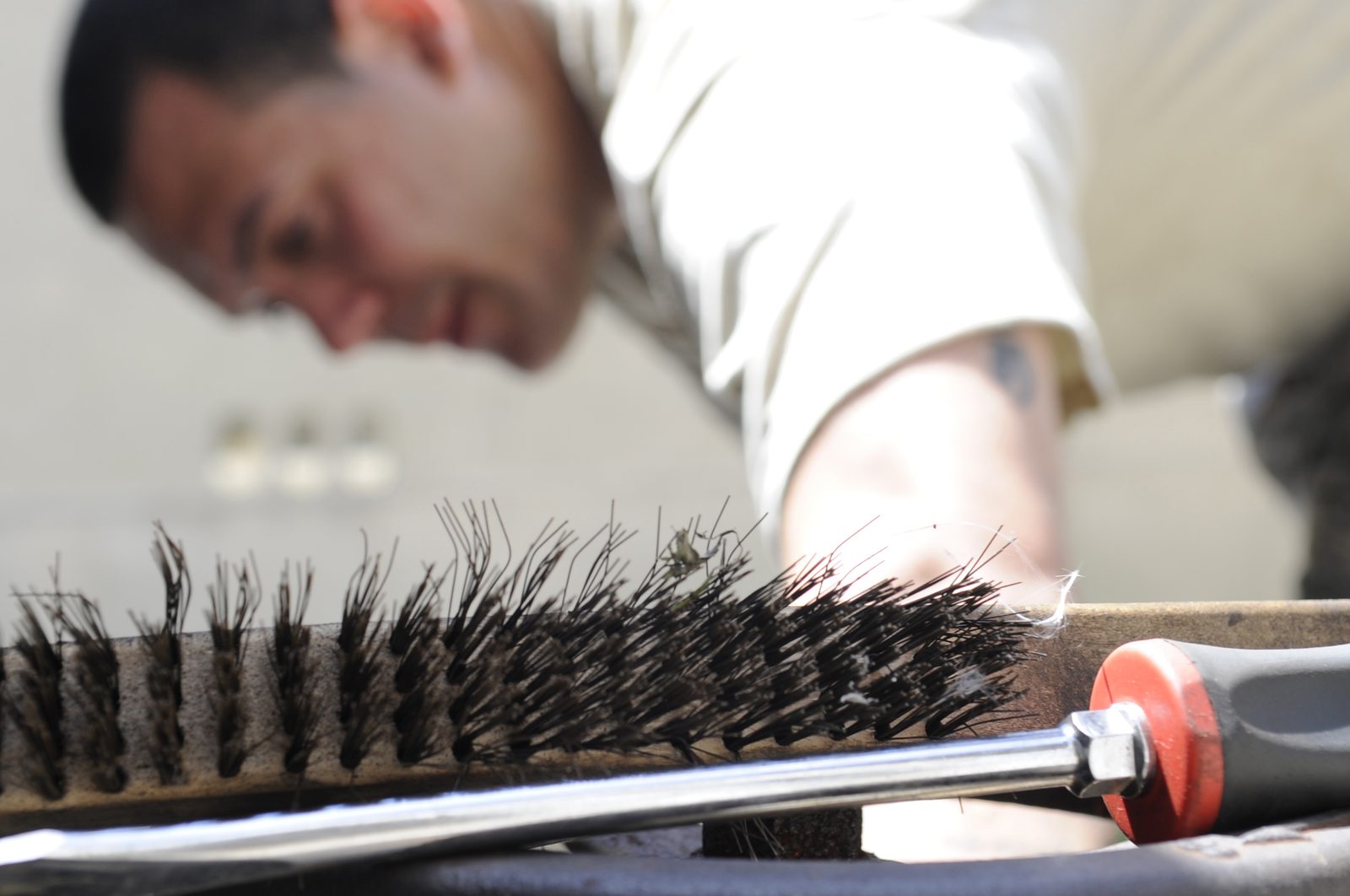 Technician brushing dirt off air conditioner coil fins